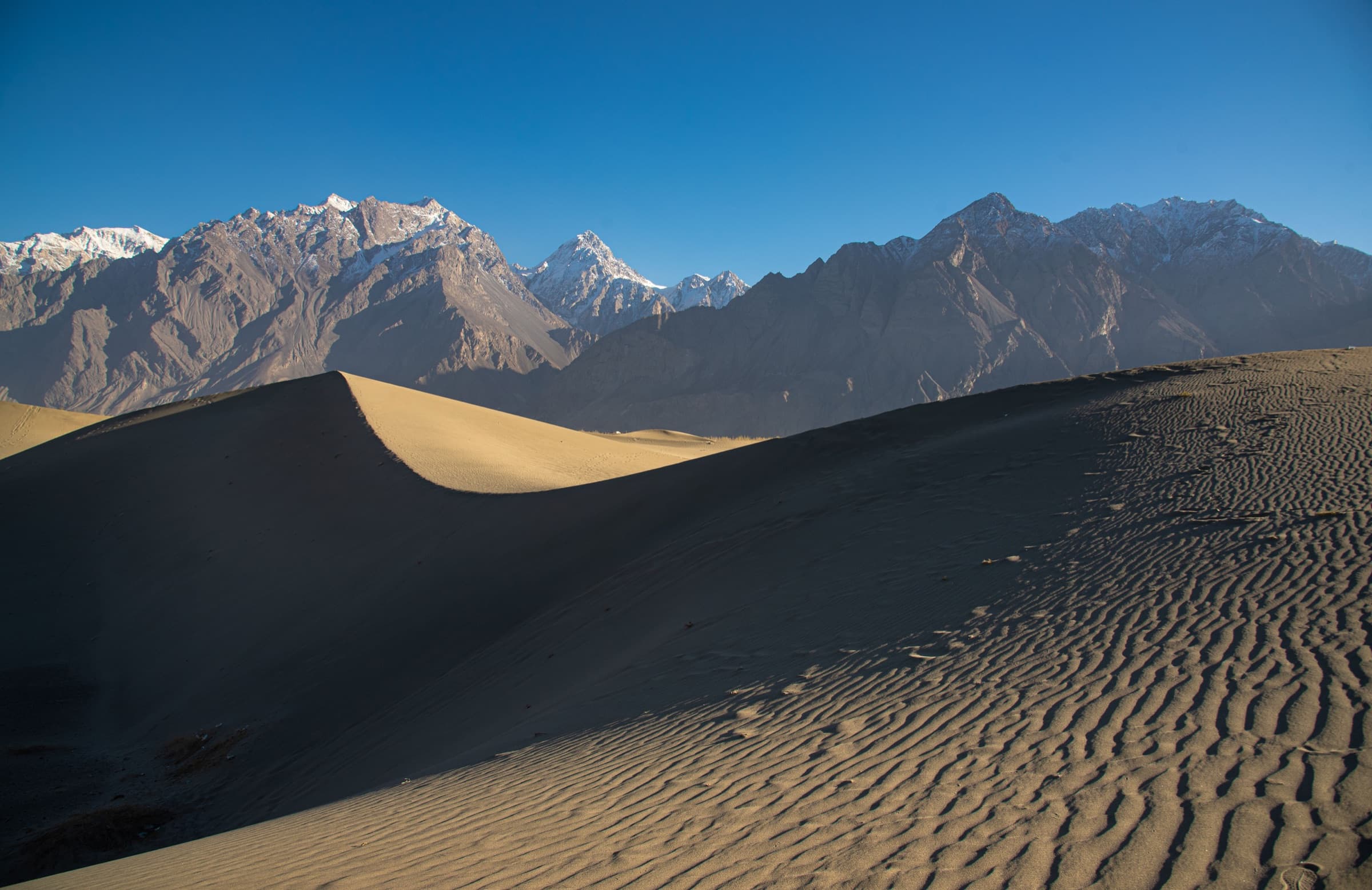 Sand dunes meeting snow-capped mountains near Skardu