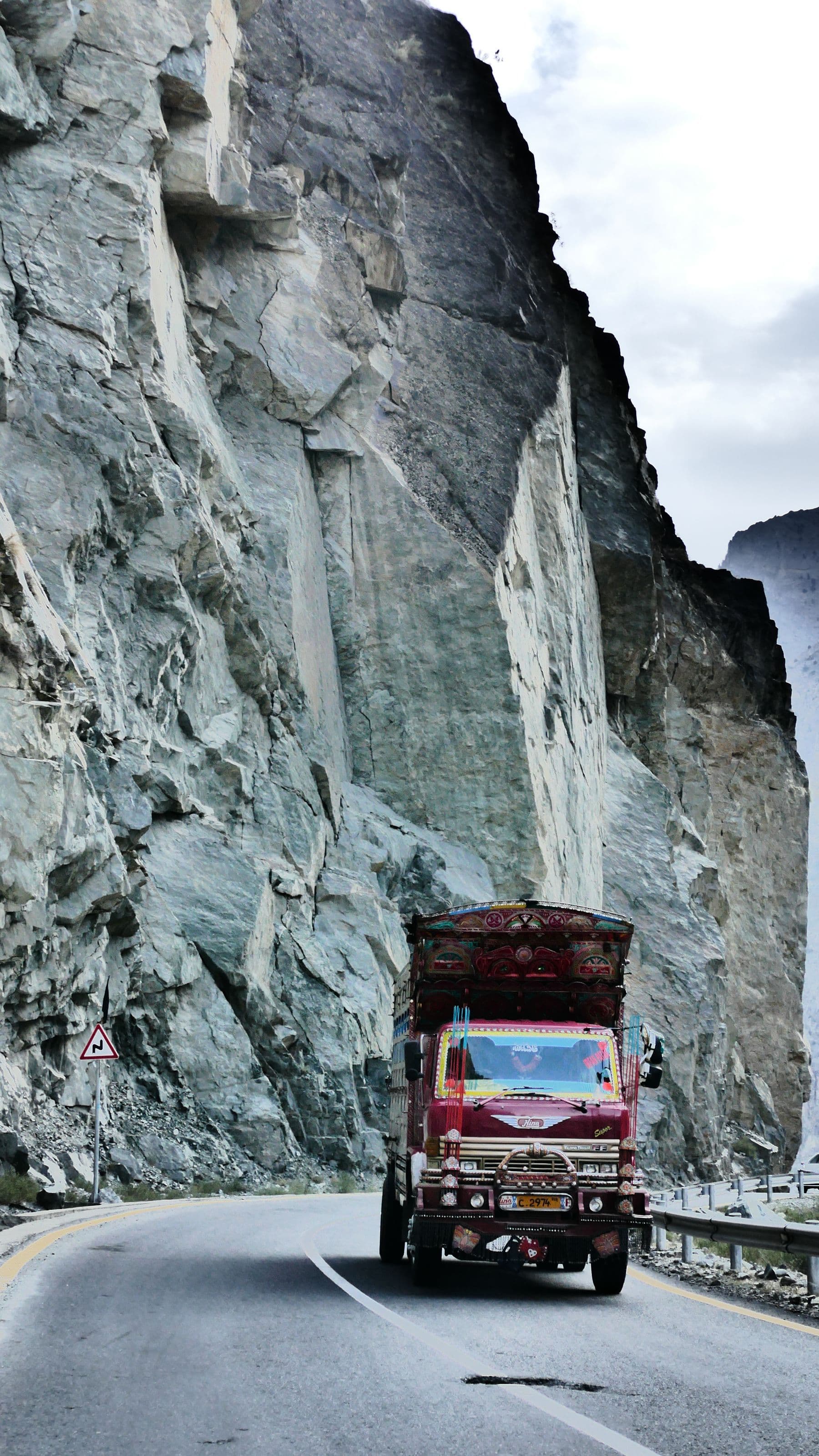 A decorated truck on the Karakoram Highway beneath rocky cliffs in Gilgit-Baltistan
